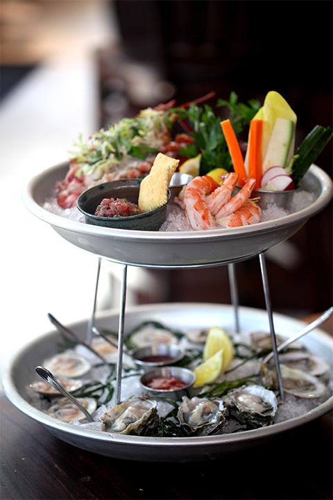 Oysters, shrimp and vegetables arranged on a tiered seafood platter