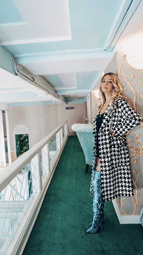 Karen Huggins wearing a checked Geegeebae coat on a balcony