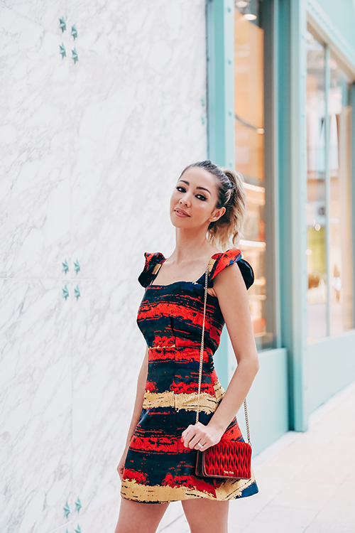 Karen Huggins in a Three Floor dress beside a white wall