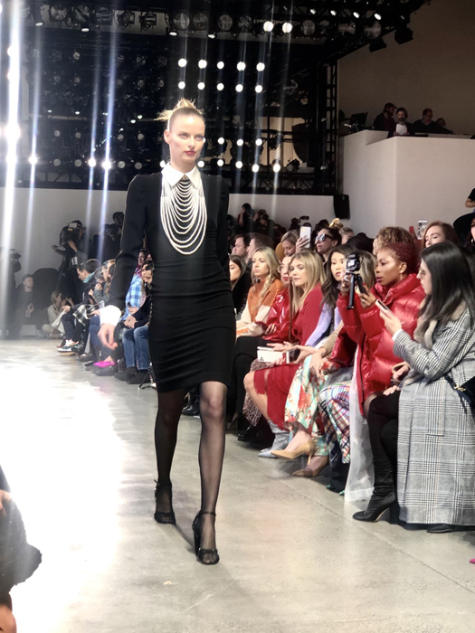 Badgley Mischka model in a black dress with layered pearl necklaces