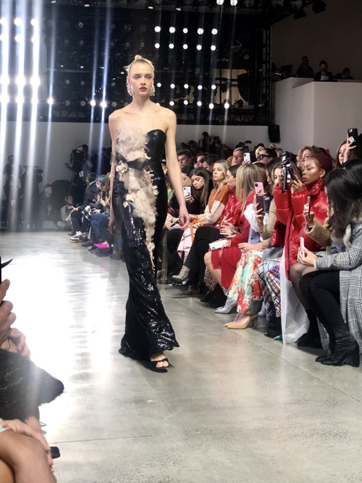 Badgley Mischka model in a strapless black gown with metallic detailing