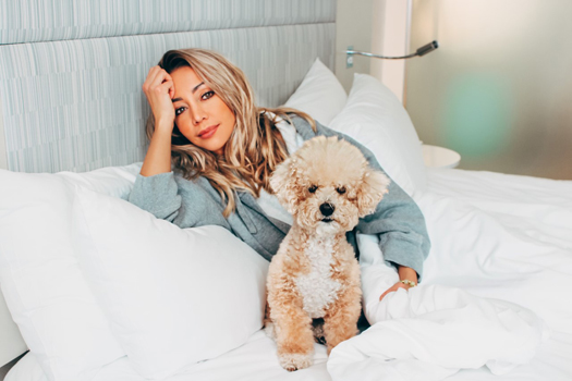 Karen Huggins and Teddy relaxing on a hotel bed