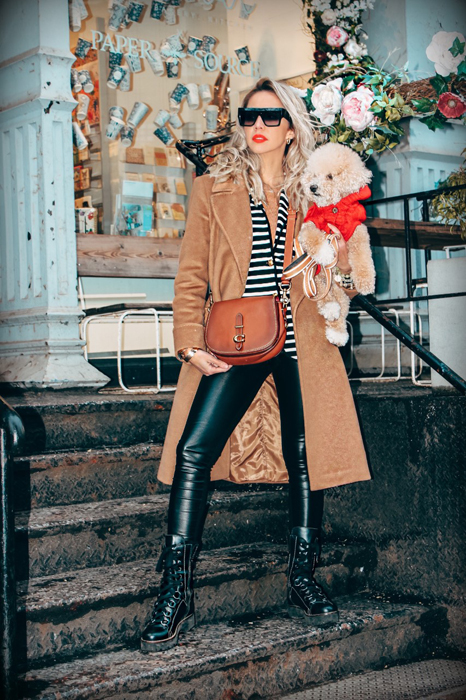 Karen Huggins wearing a camel coat and holding Teddy during New York Fashion Week