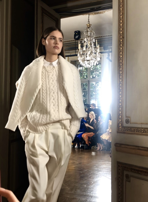 Ryan Roche model in an ivory knit outfit with a coat draped over the shoulders