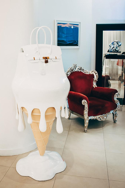 White handbag sculpture on an ice-cream-cone base beside a red chair