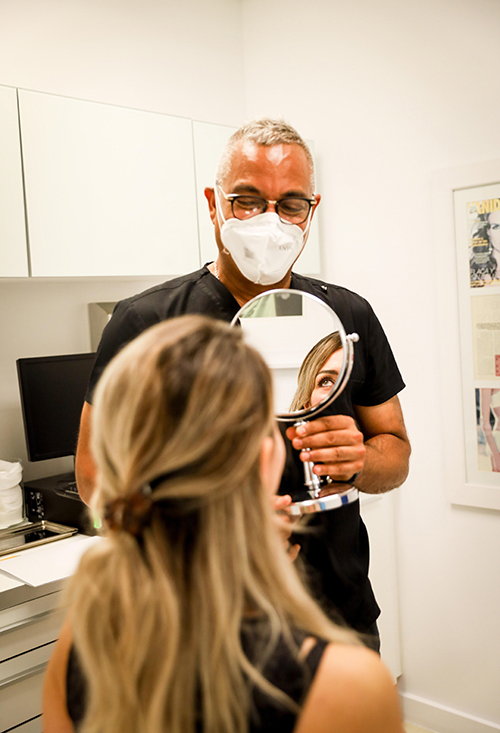 Karen Huggins looking in a mirror held by Dr. Jhonny Salomon