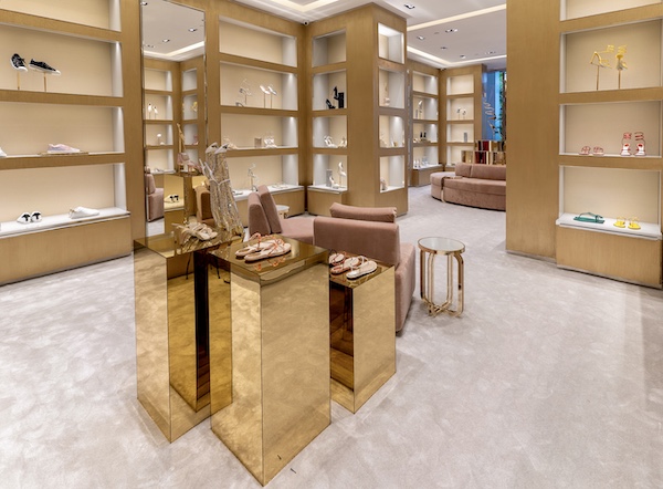 Reflective gold display tables and shoe shelves inside the René Caovilla boutique.