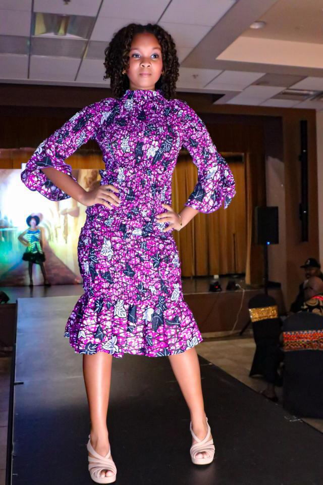 Sophia Rose Hinkson posing on a runway in a purple patterned dress.