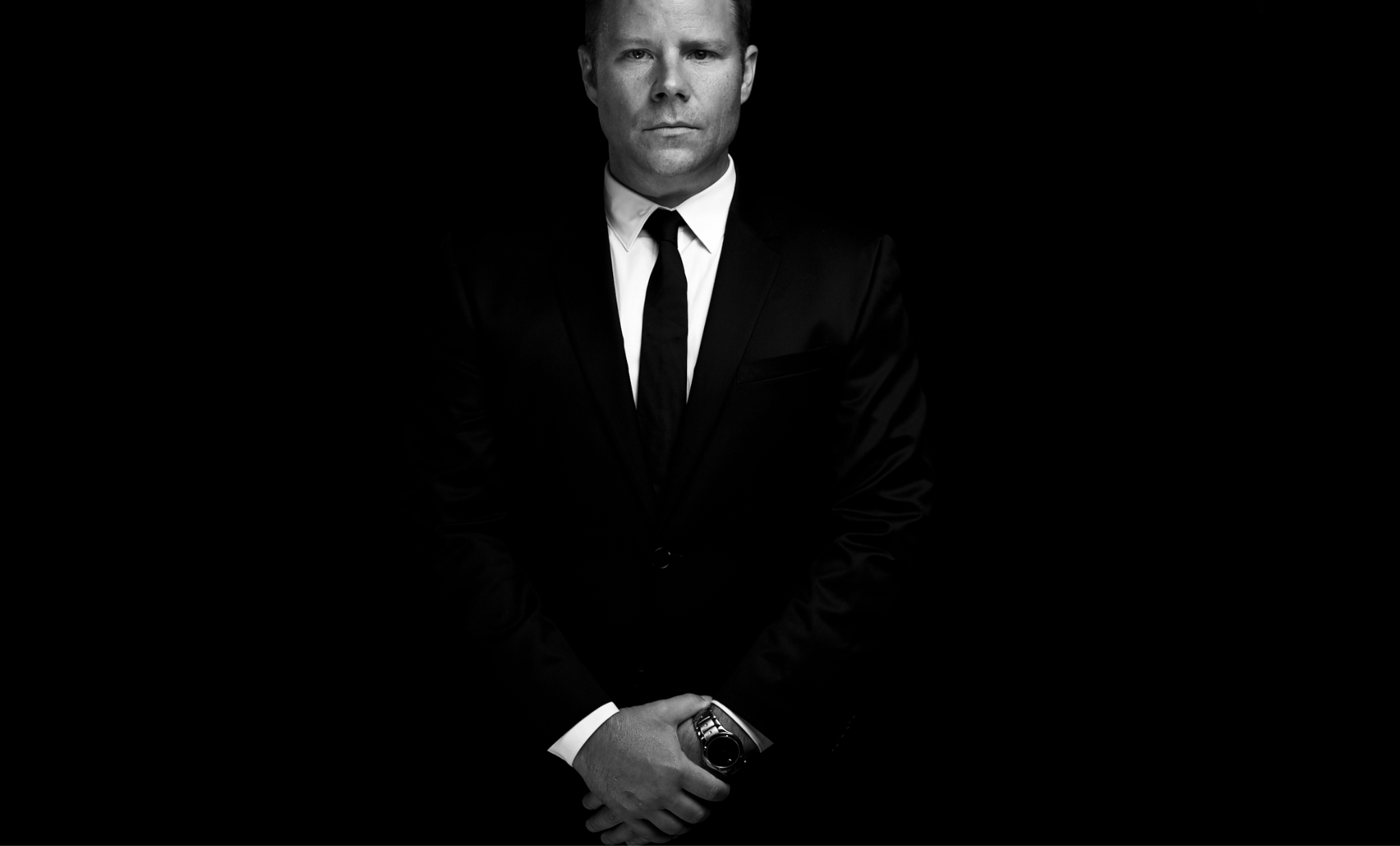 Chris Lavoie in a black suit against a black background, featured portrait for Miami SHOOT Magazine