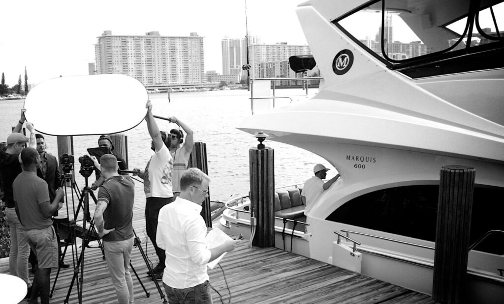 Chris Lavoie reviewing production notes during a film shoot at a Miami marina alongside film crew.