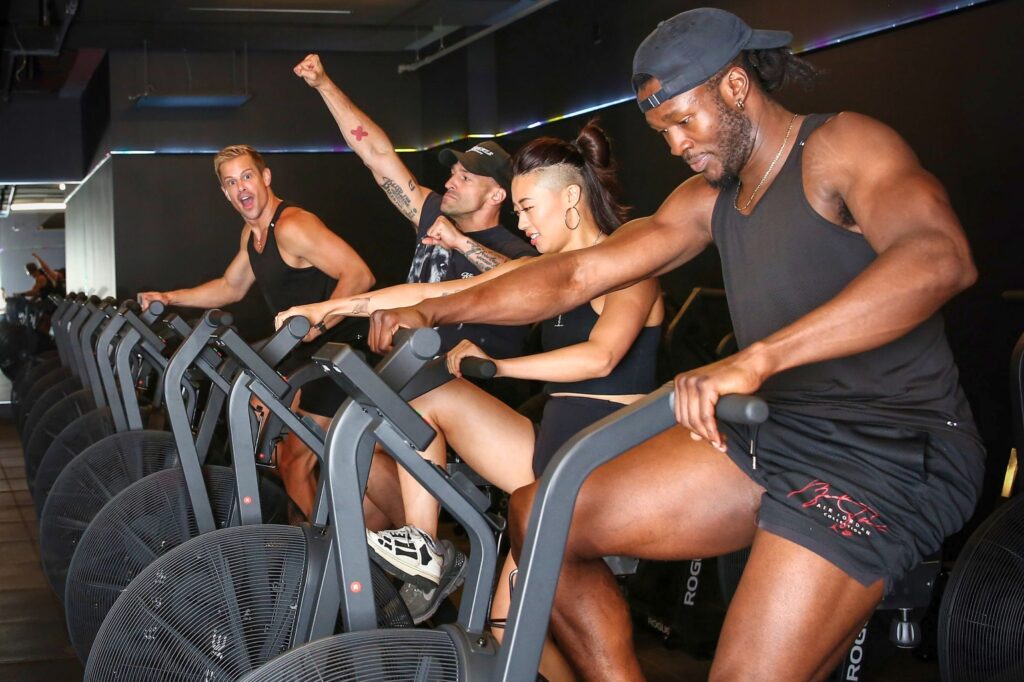 Members of The Pack participate in a high-energy Assault Bike training session, reflecting Noah Neiman's community-driven approach to fitness and performance.