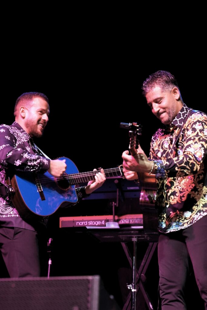 Guitarists performing together during the Miami concert