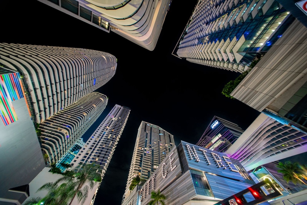 Looking upward between illuminated Brickell towers against the night sky