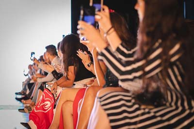 Front-row guests watching a fashion runway presentation.