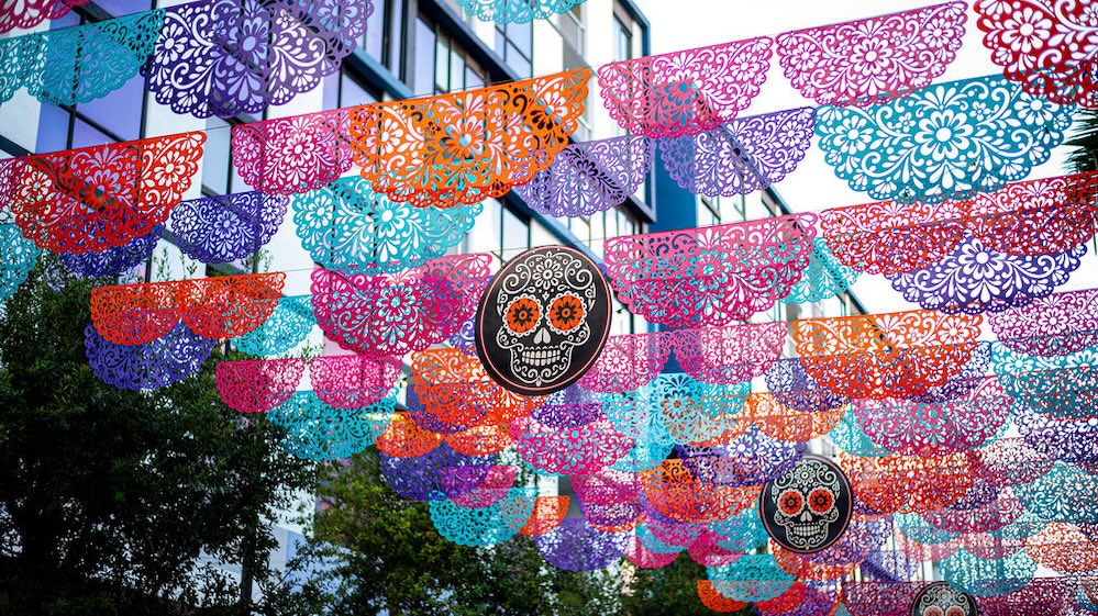 Colorful papel picado-style banners and decorative skull medallions suspended above CityPlace Doral.